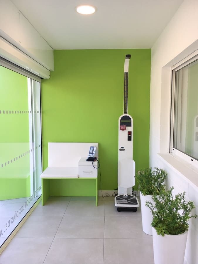 Una habitación con una pared verde y un banco blanco.