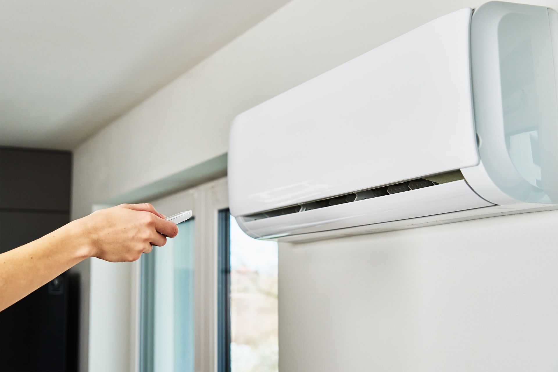 Main actionnant une télécommande pour la climatisation