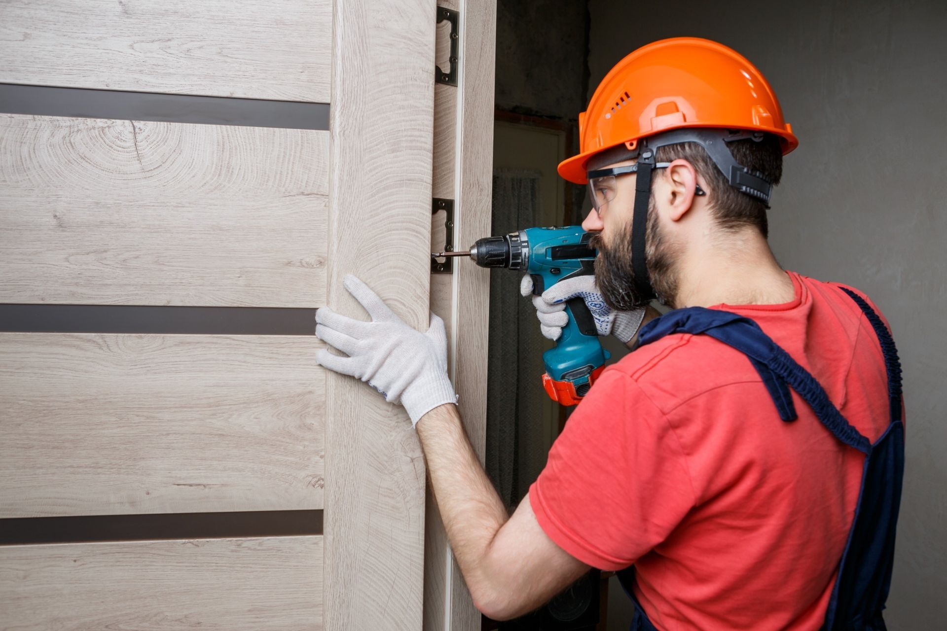 Un hombre está instalando una puerta con un taladro.