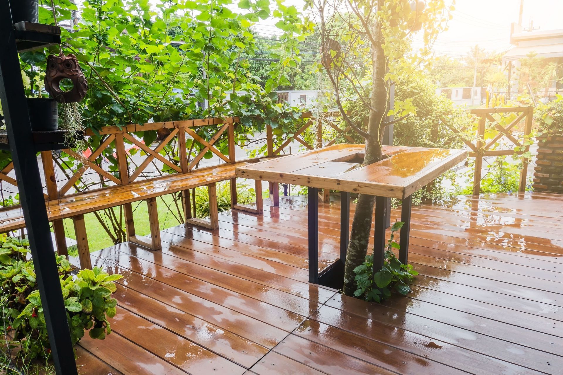 Una terraza de madera con un banco y una mesa en un día lluvioso.