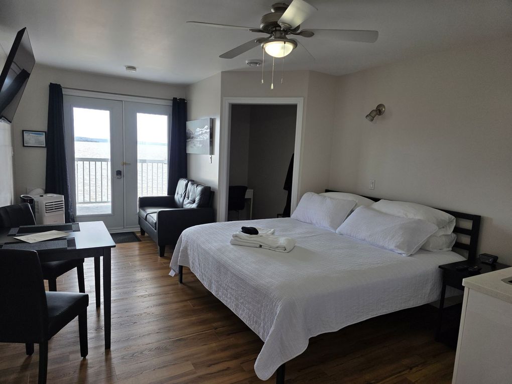 Spacious bedroom with a large bed, ceiling fan, desk, and French doors leading to a balcony.