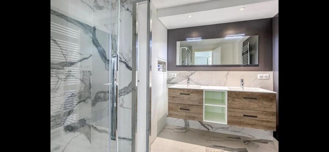 Salle de bains moderne avec douche vitrée, double vasque et grand miroir