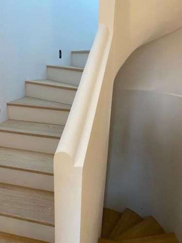 Escalier intérieur avec des marches beiges et une rampe blanche incurvée