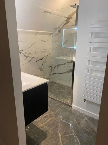 Salle de bains moderne avec carrelage imitation marbre, douche à l’italienne.