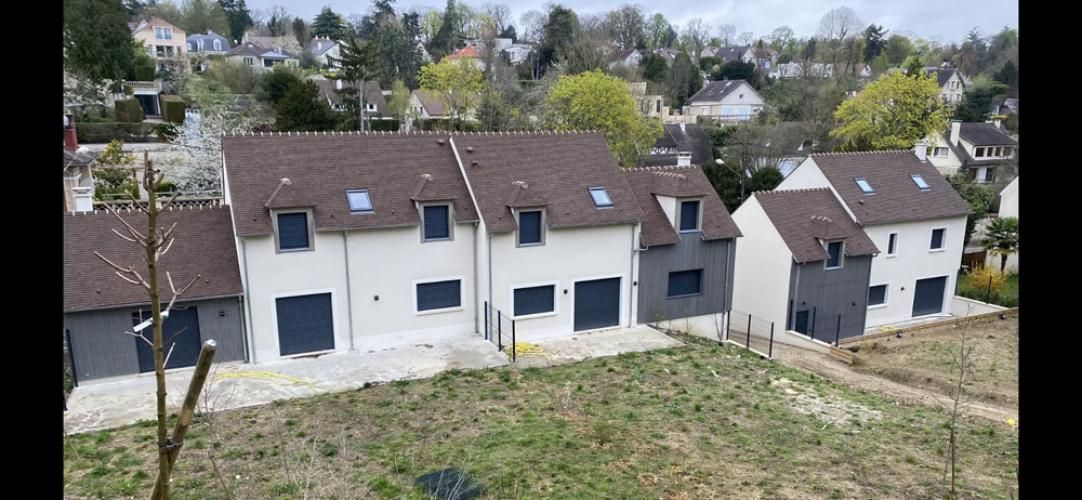 Rangée de maisons blanches aux toits bruns sur une pente herbeuse, dans un quartier résidentiel en périphérie de la ville