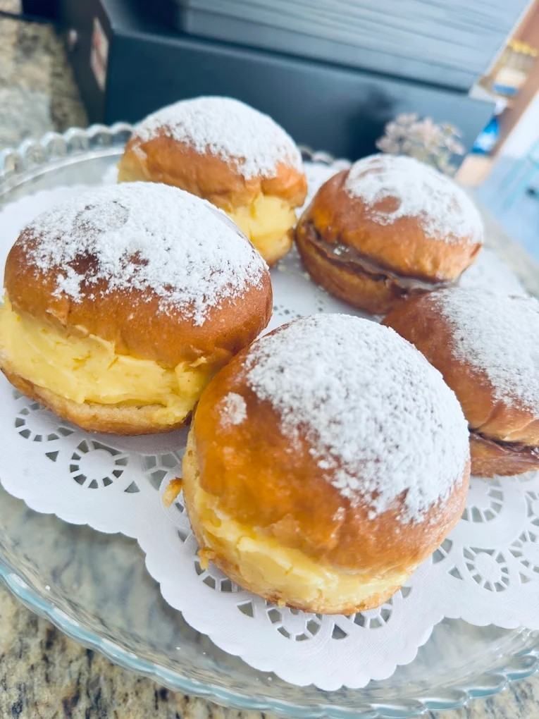 Donas con azúcar glas en una bandeja de vidrio con tapetes blancos.