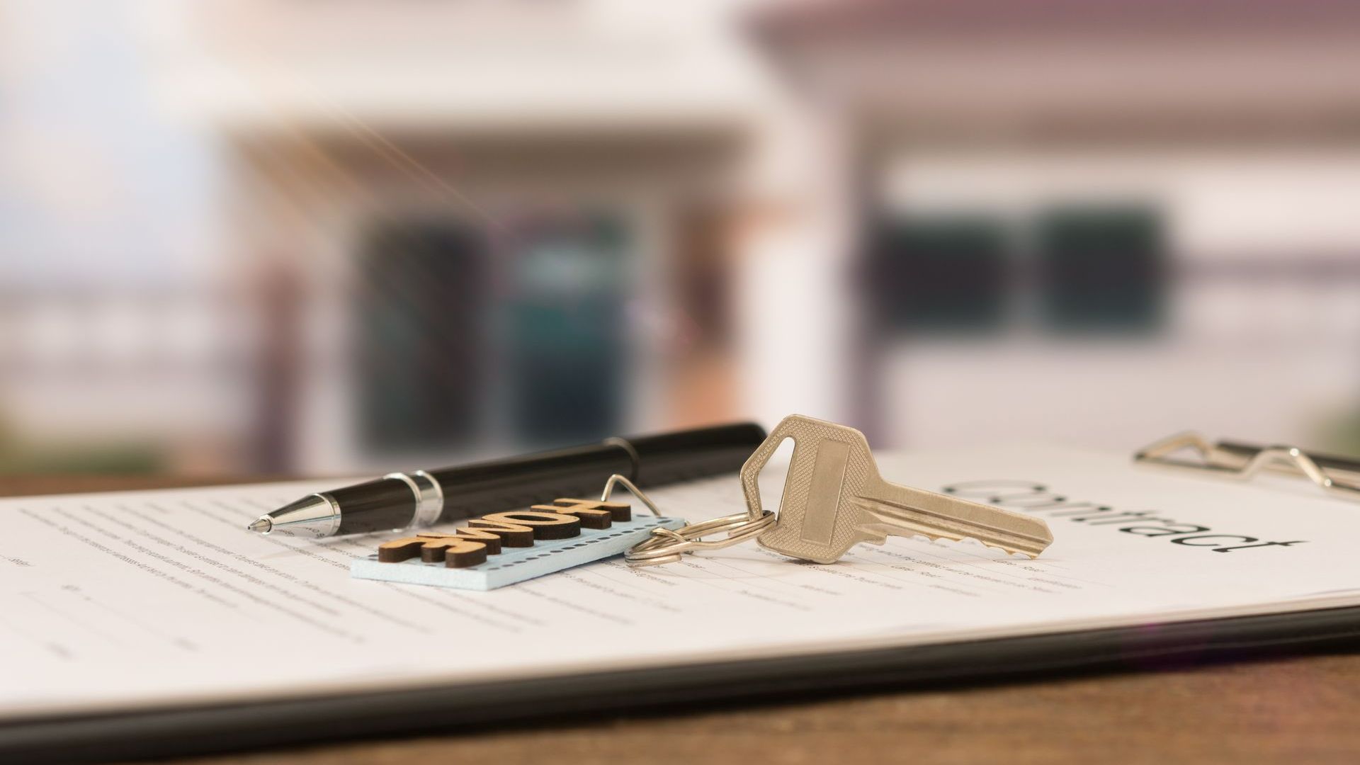 Un stylo et des clés de maison posés sur un contrat immobilier