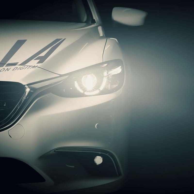 Primer plano de la parte delantera de un coche blanco con faros brillantes y las letras