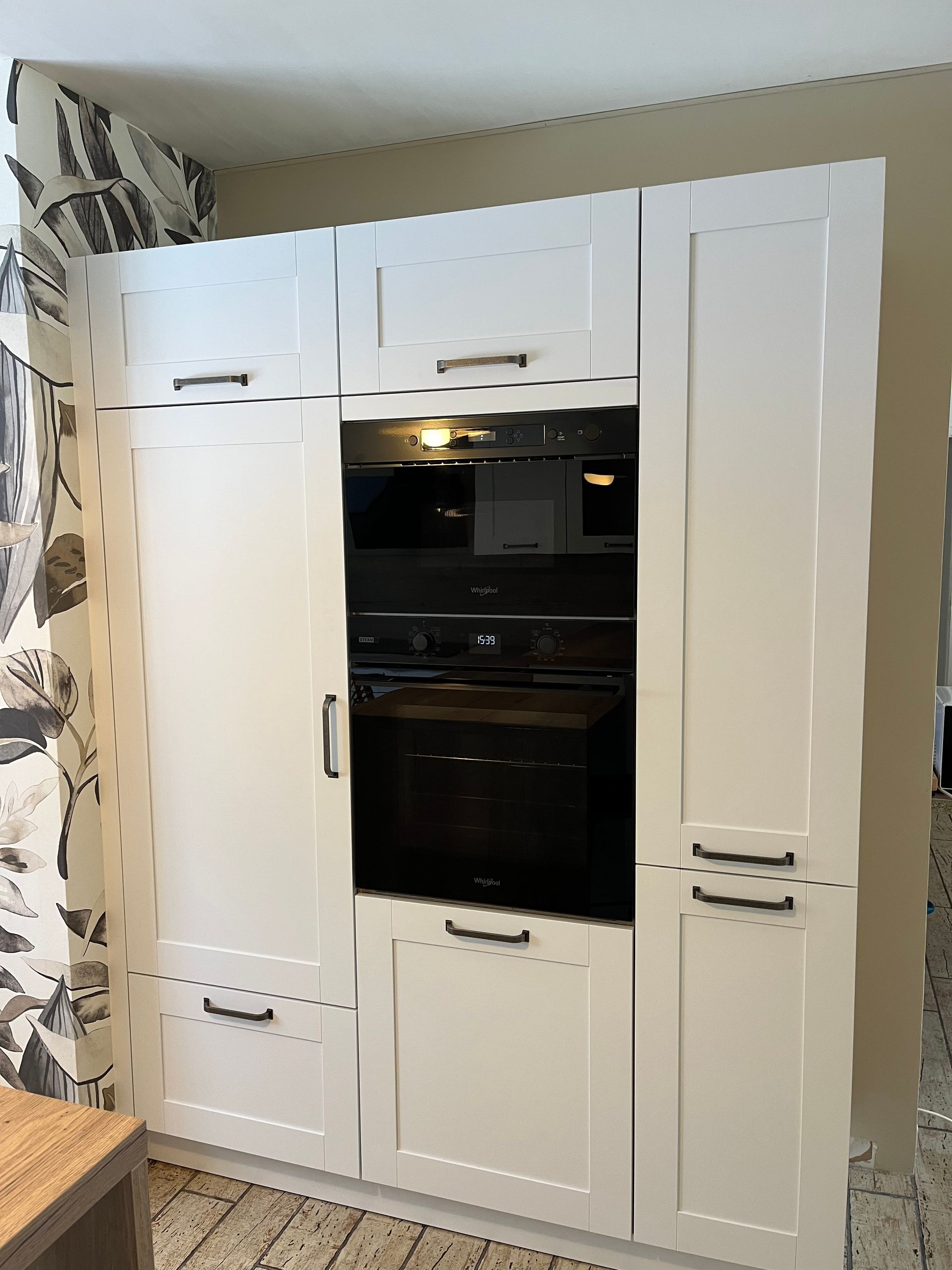 Cuisine équipée de placards blancs et d'un four noir intégré.