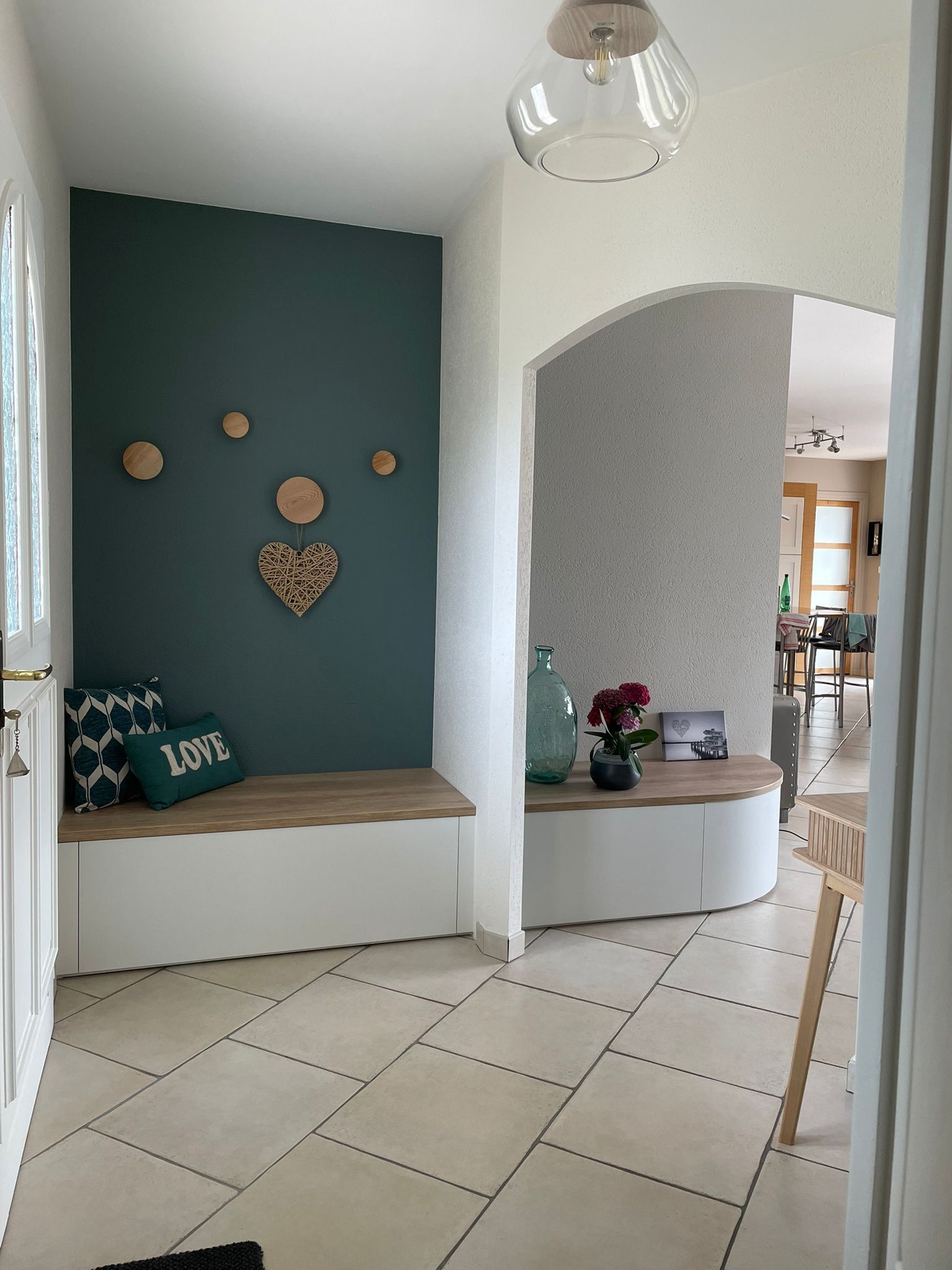 Entrée avec mur d'accent turquoise, banquette intégrée, décoration en forme de cœur et sol carrelé.