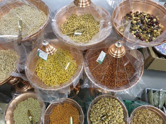 Various dried grains and spices in copper bowls, ready for sale.