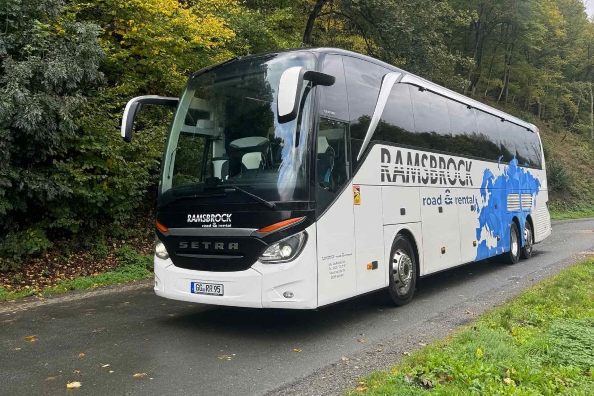 Ein weiß-blauer Bus fährt eine Straße entlang.
