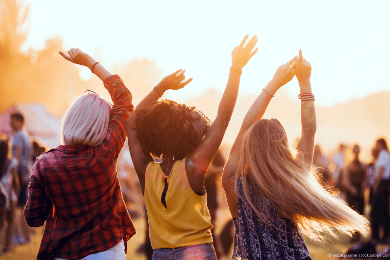 Eine Gruppe von Frauen tanzt bei einem Musikfestival mit erhobenen Armen.