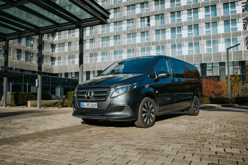 Ein schwarzer Lieferwagen steht vor einem großen Gebäude.