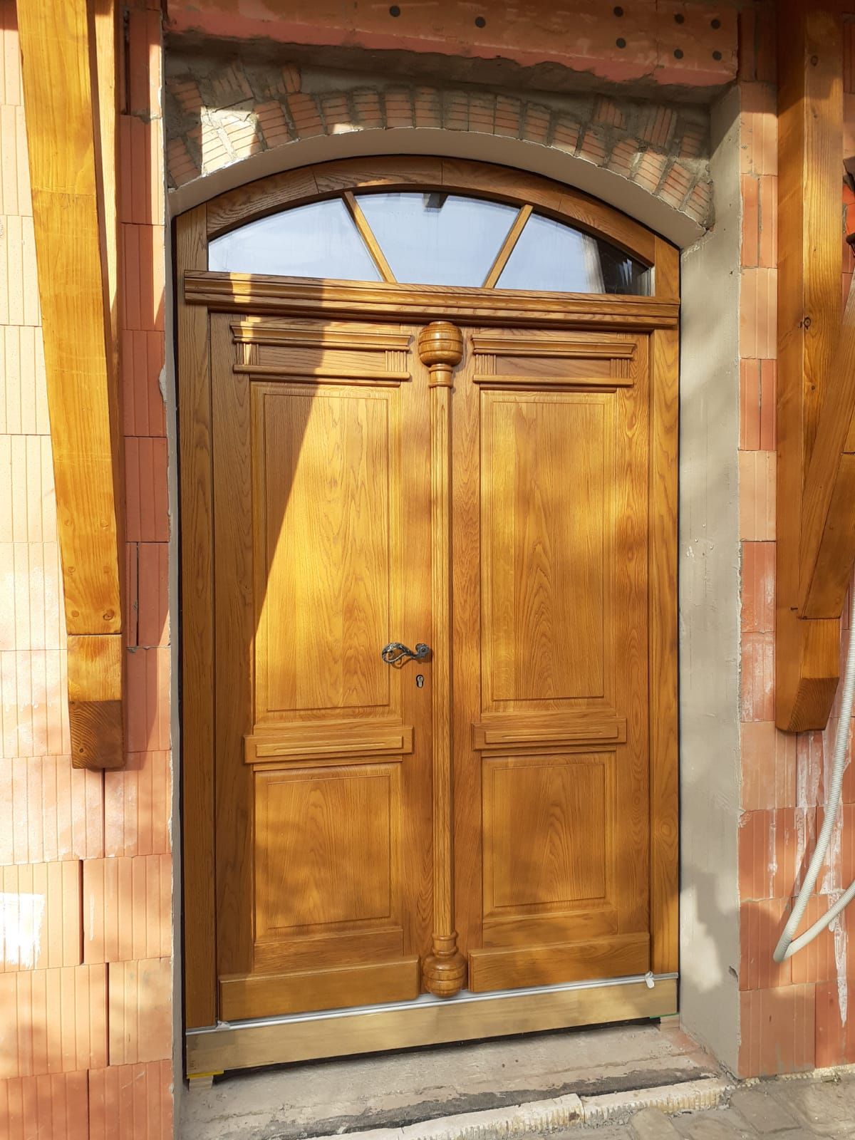 Doppelte Holztüren mit Glasscheiben in einem weiß getünchten Raum mit dunklem Holzboden.