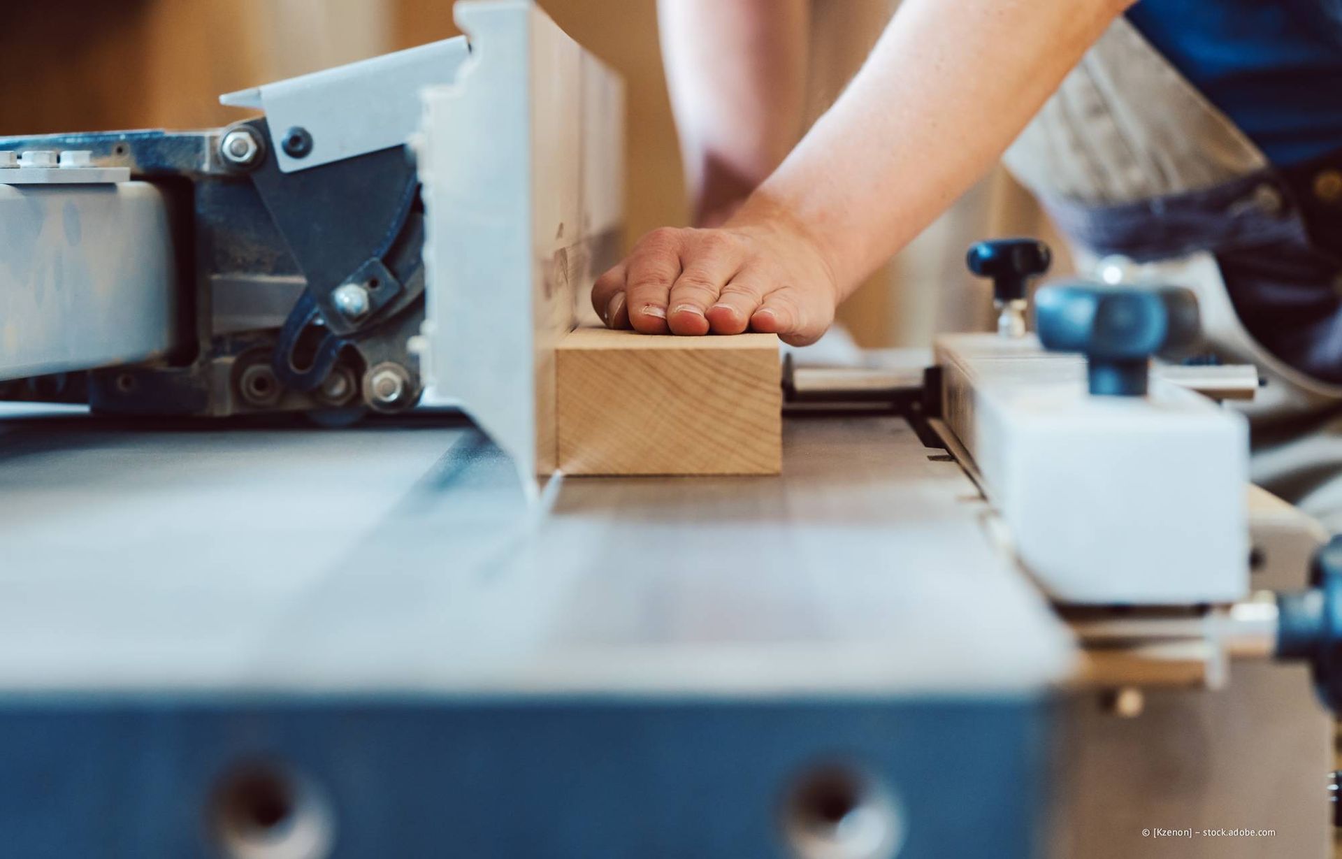 Person, die mit einer Abrichte einen Holzblock hobelt, Hände am Block, Werkstattumgebung.