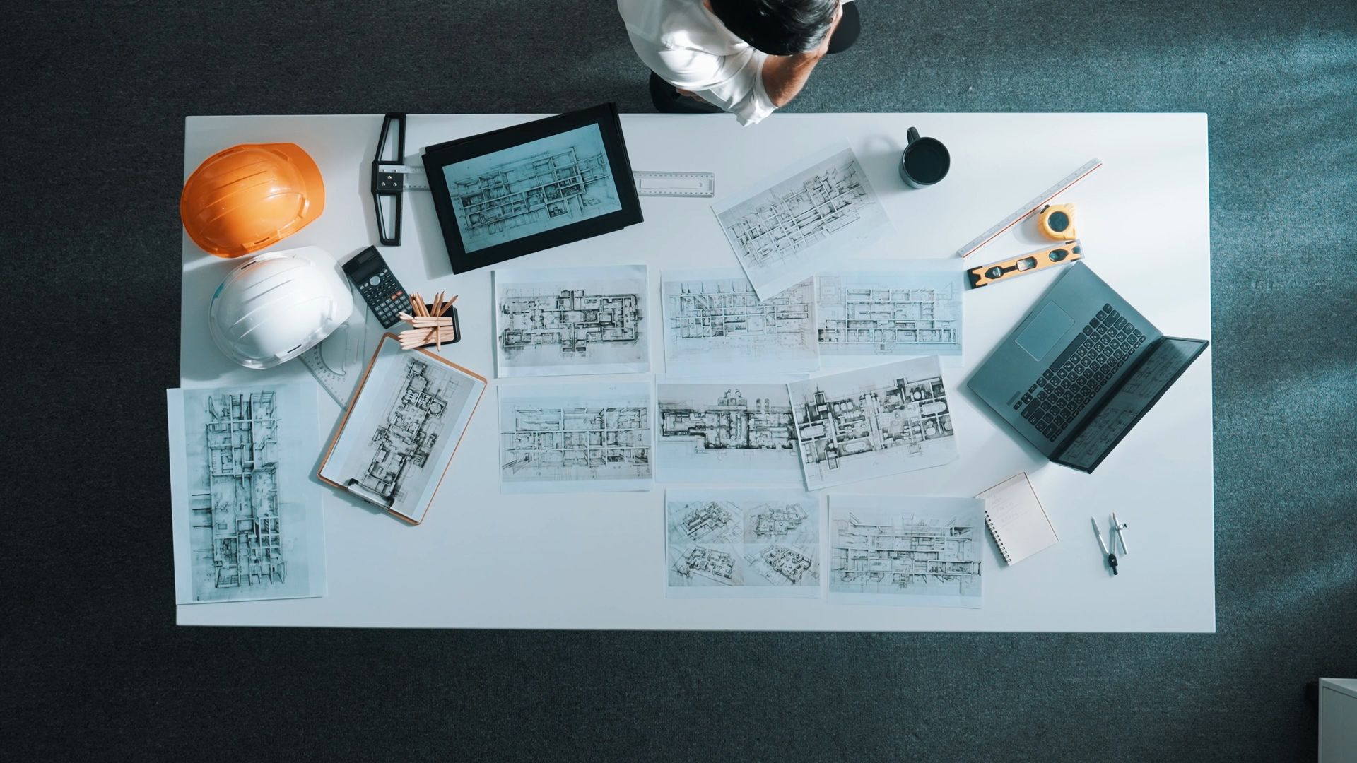 Vue de dessus d'un bureau avec des croquis, des carnets, une tablette et des outils de dessin.
