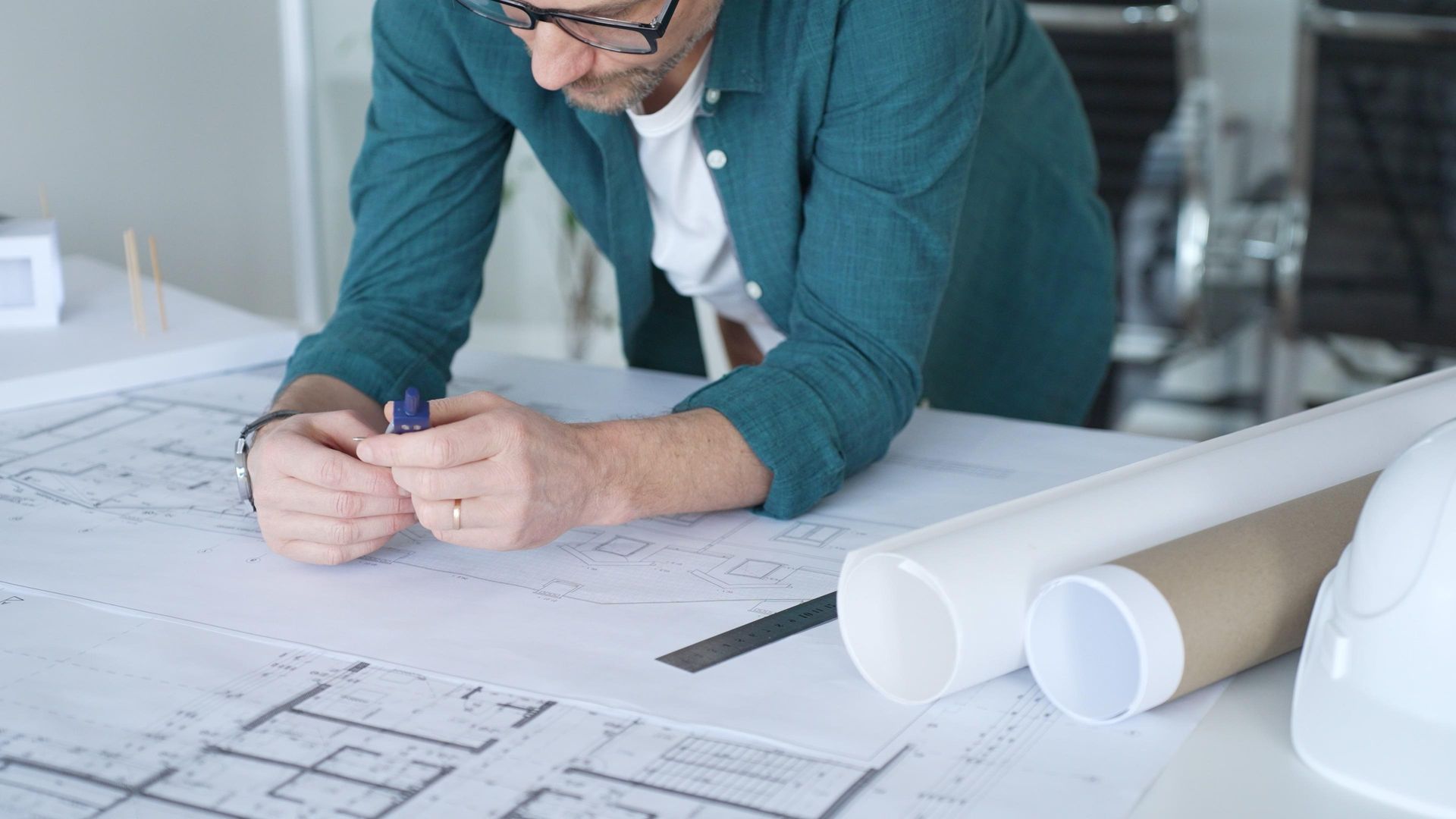 Un architecte examine des plans étalés sur un bureau.