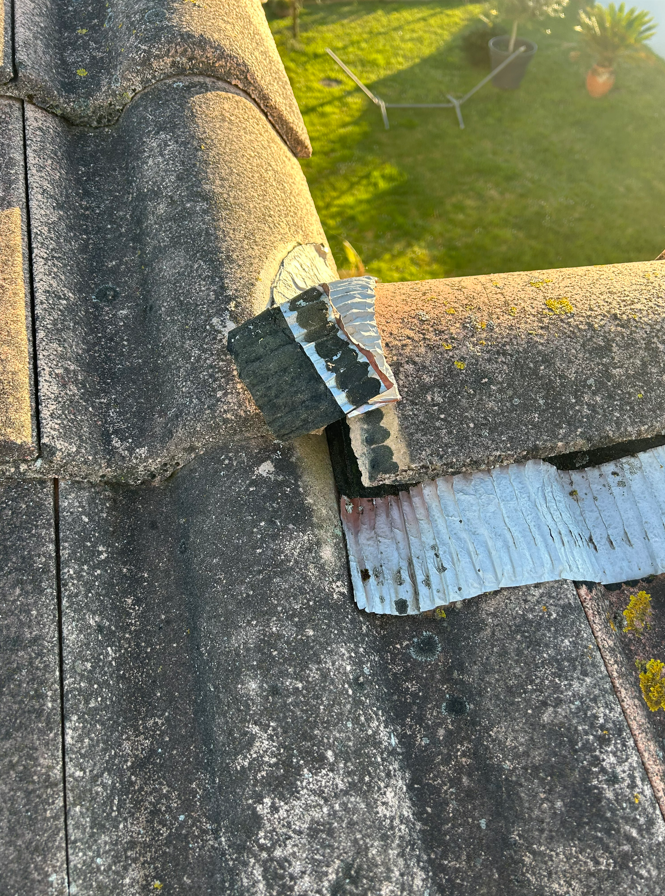 Bardeaux de toiture endommagés avec une pièce de solin métallique pliée au-dessus du bord d'une gouttière.