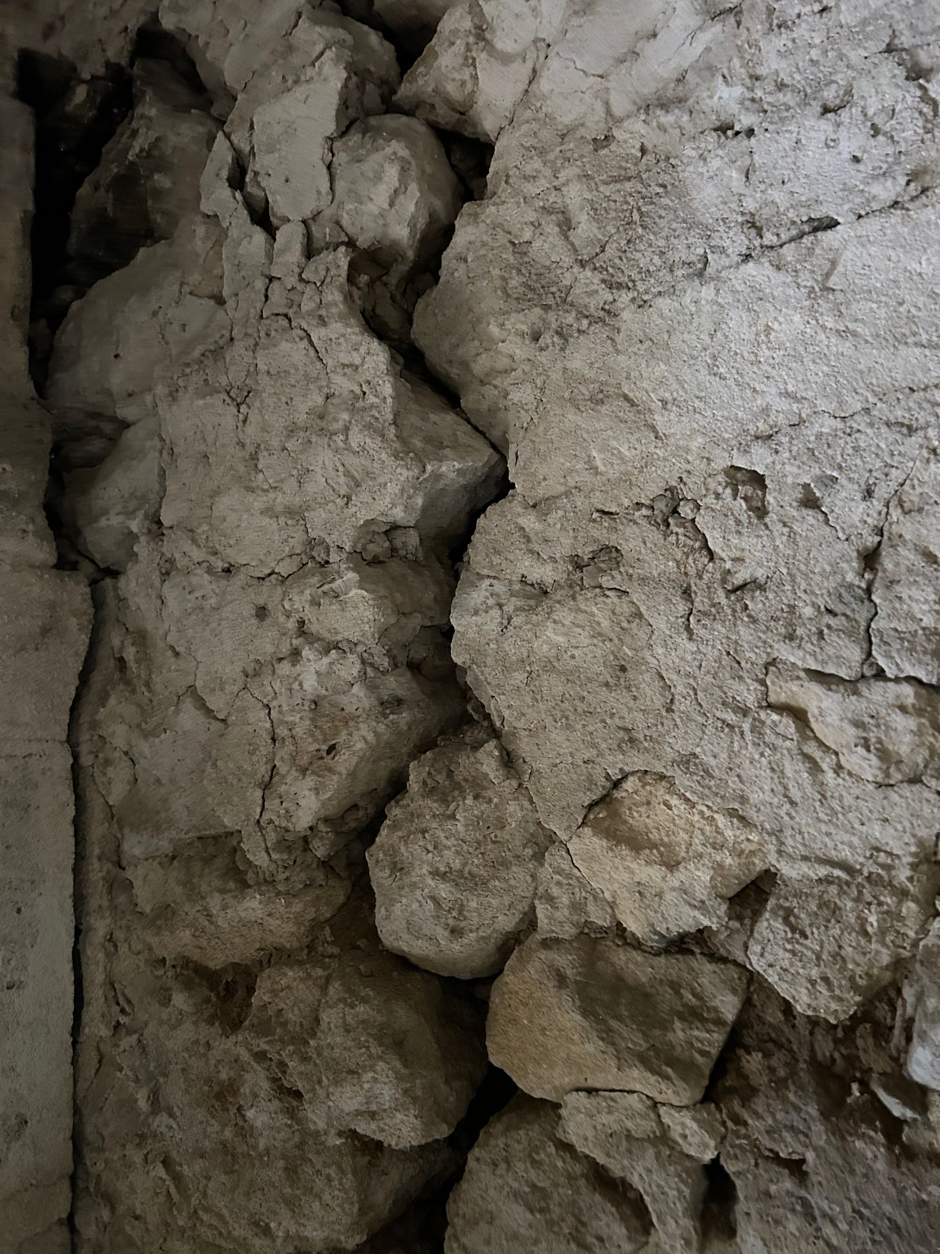 Gros plan sur un mur rugueux, à la texture craquelée et irrégulière.