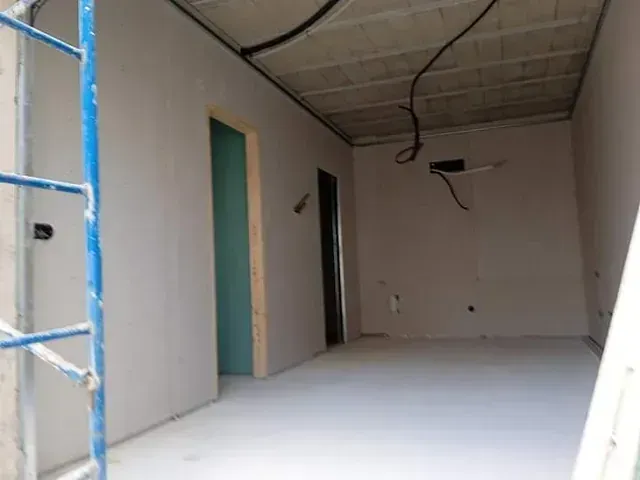 Habitación en construcción, con paredes y techo de yeso laminado y puertas abiertas.