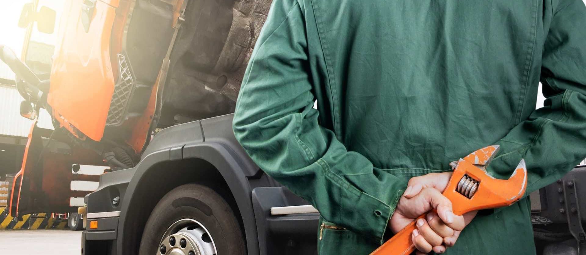 Un mecánico sostiene una llave naranja delante de un camión.