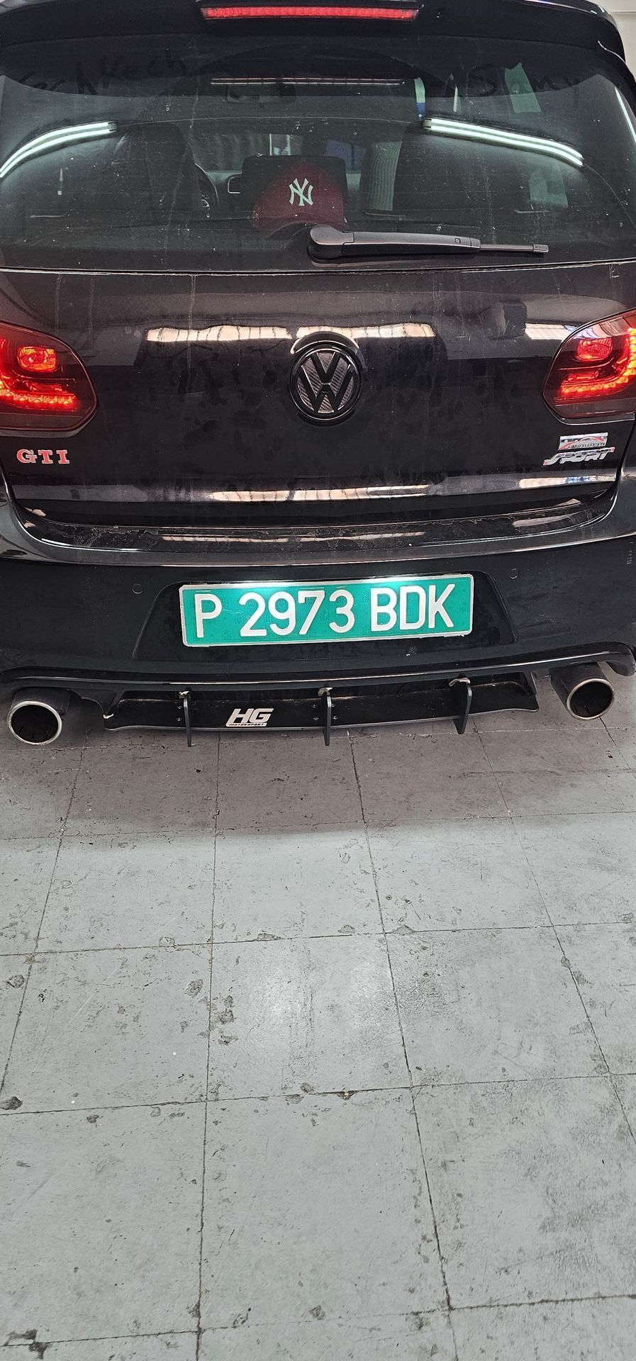 Un coche negro con matrícula verde está aparcado en un garaje.