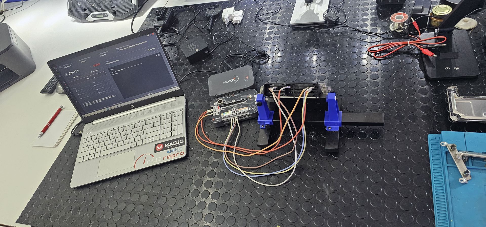 Hay una computadora portátil sobre una mesa al lado de un montón de cables.