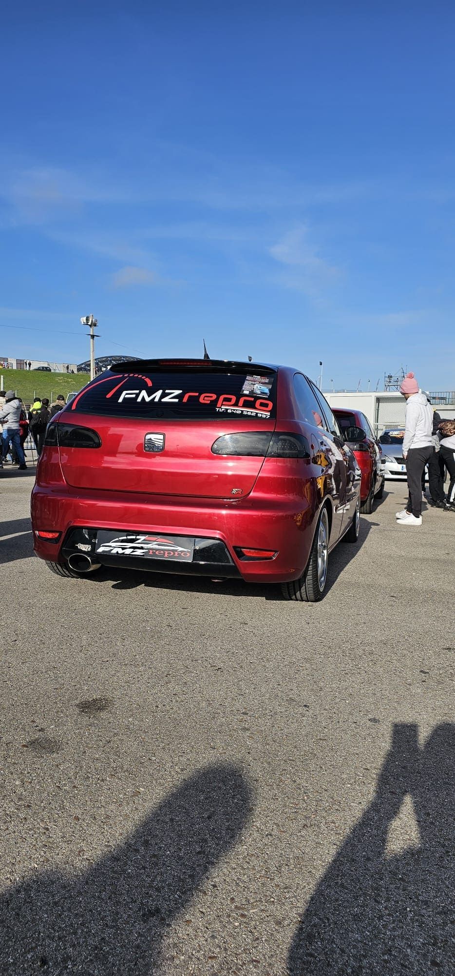 Un coche rojo está aparcado en un estacionamiento.