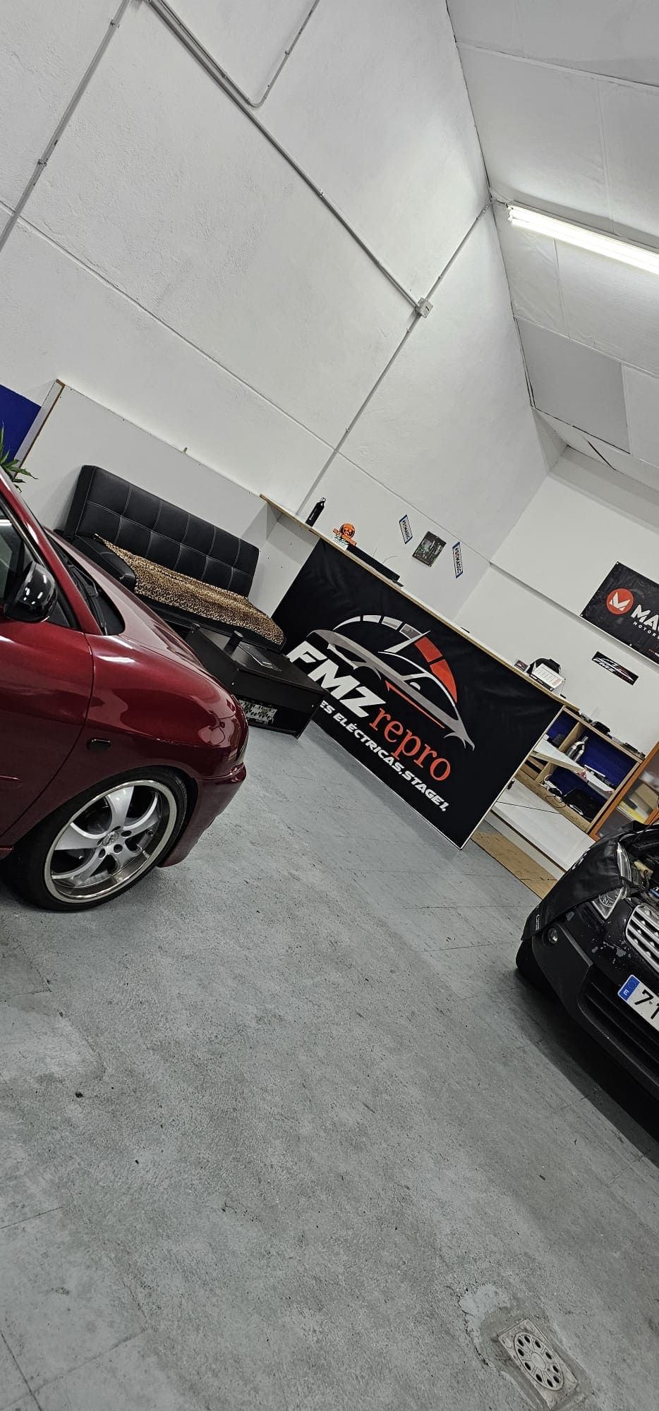 Un coche rojo está aparcado en un garaje al lado de un cartel de Pizza Hut.