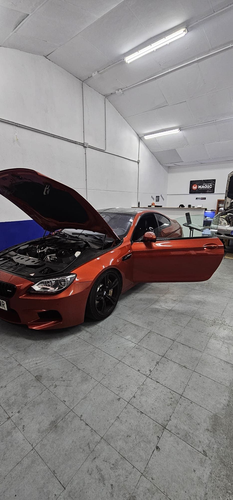 Un coche deportivo rojo está aparcado en un garaje con el capó abierto.