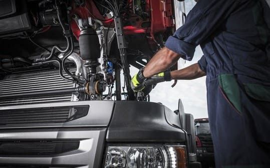 Un hombre está trabajando en el motor de un camión.