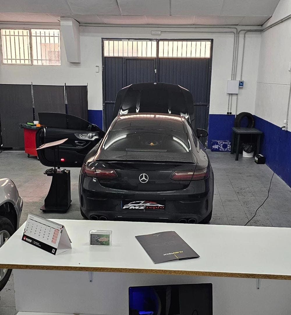 Un coche está aparcado en un garaje con el capó levantado.