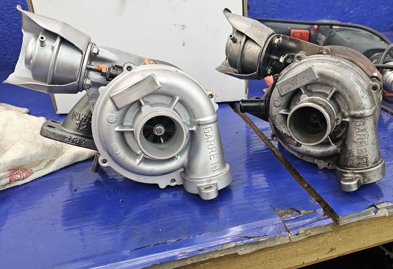 Hay dos turbocompresores sobre una mesa azul.