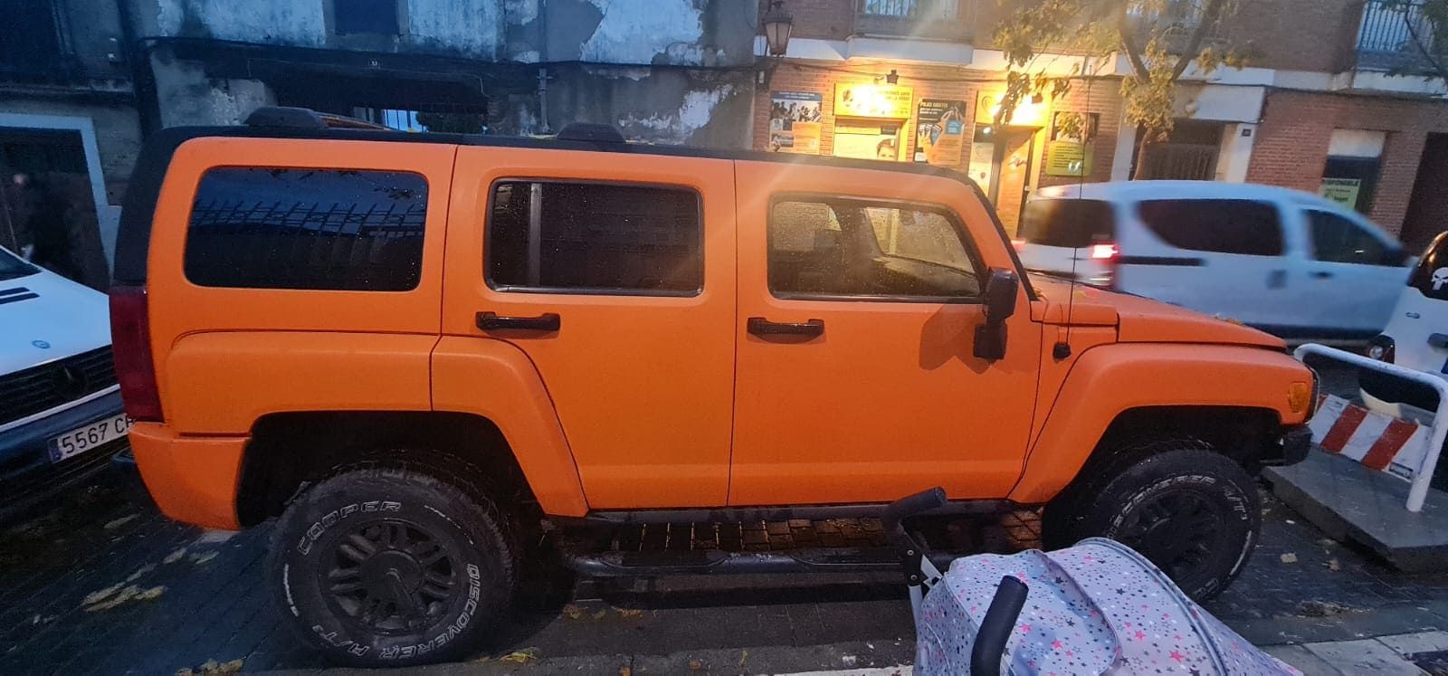 Un gran jeep naranja está estacionado al costado de la carretera.