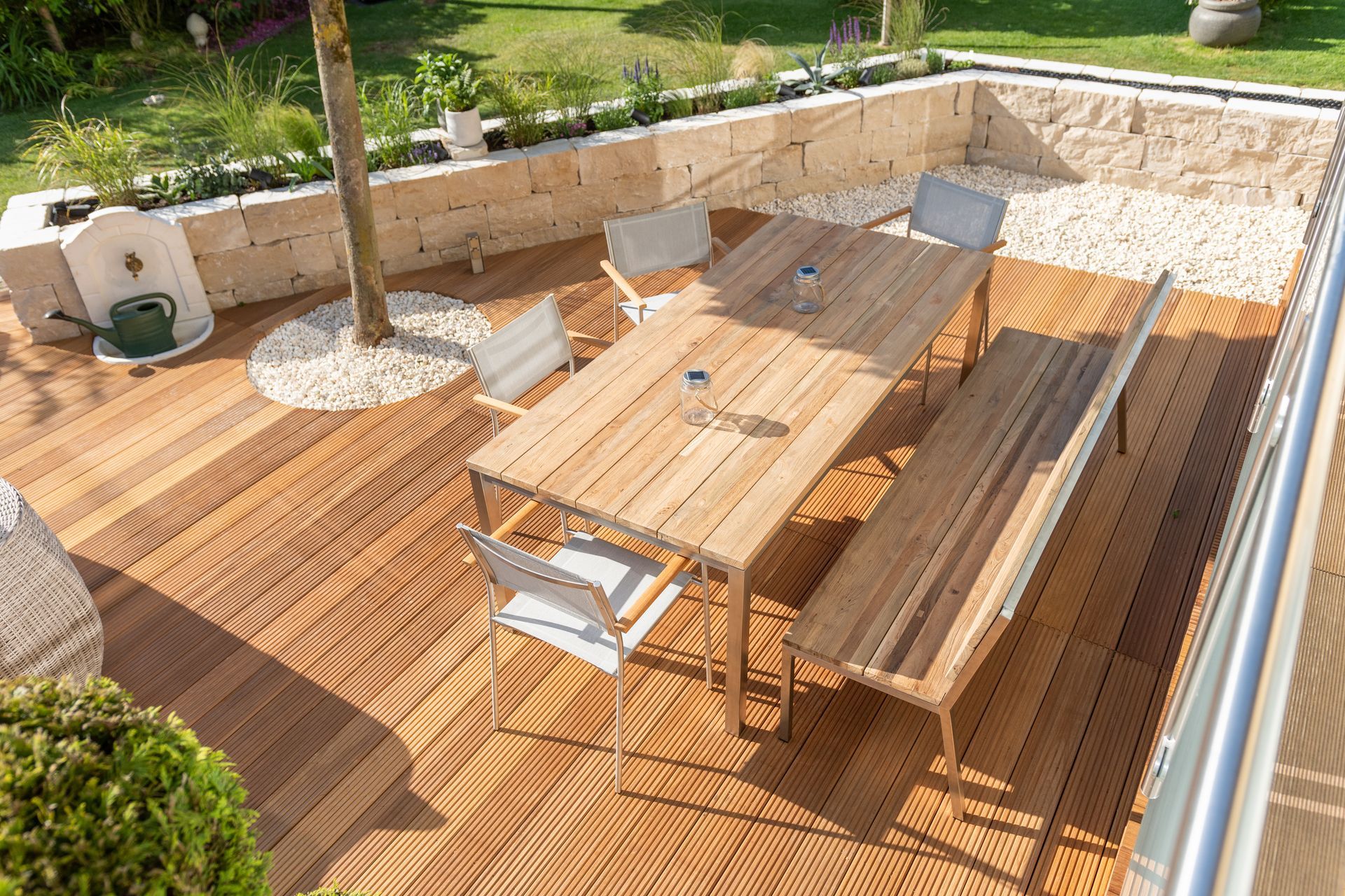 Terrasse extérieure en bois avec table, bancs et chaises dans un patio ensoleillé