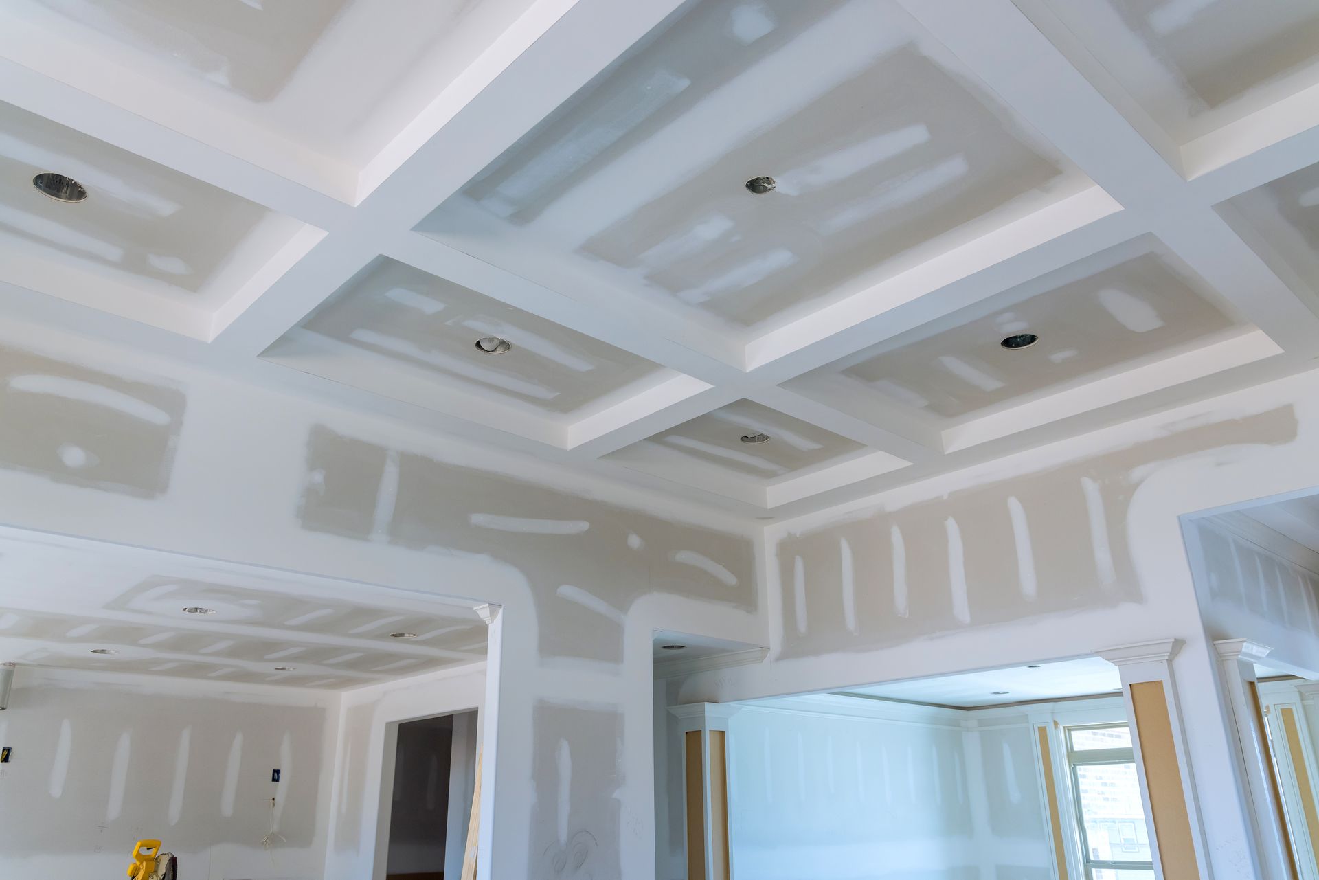 Plafond intérieur inachevé avec panneaux de plaques de plâtre blanches, spots encastrés et joints apparents.