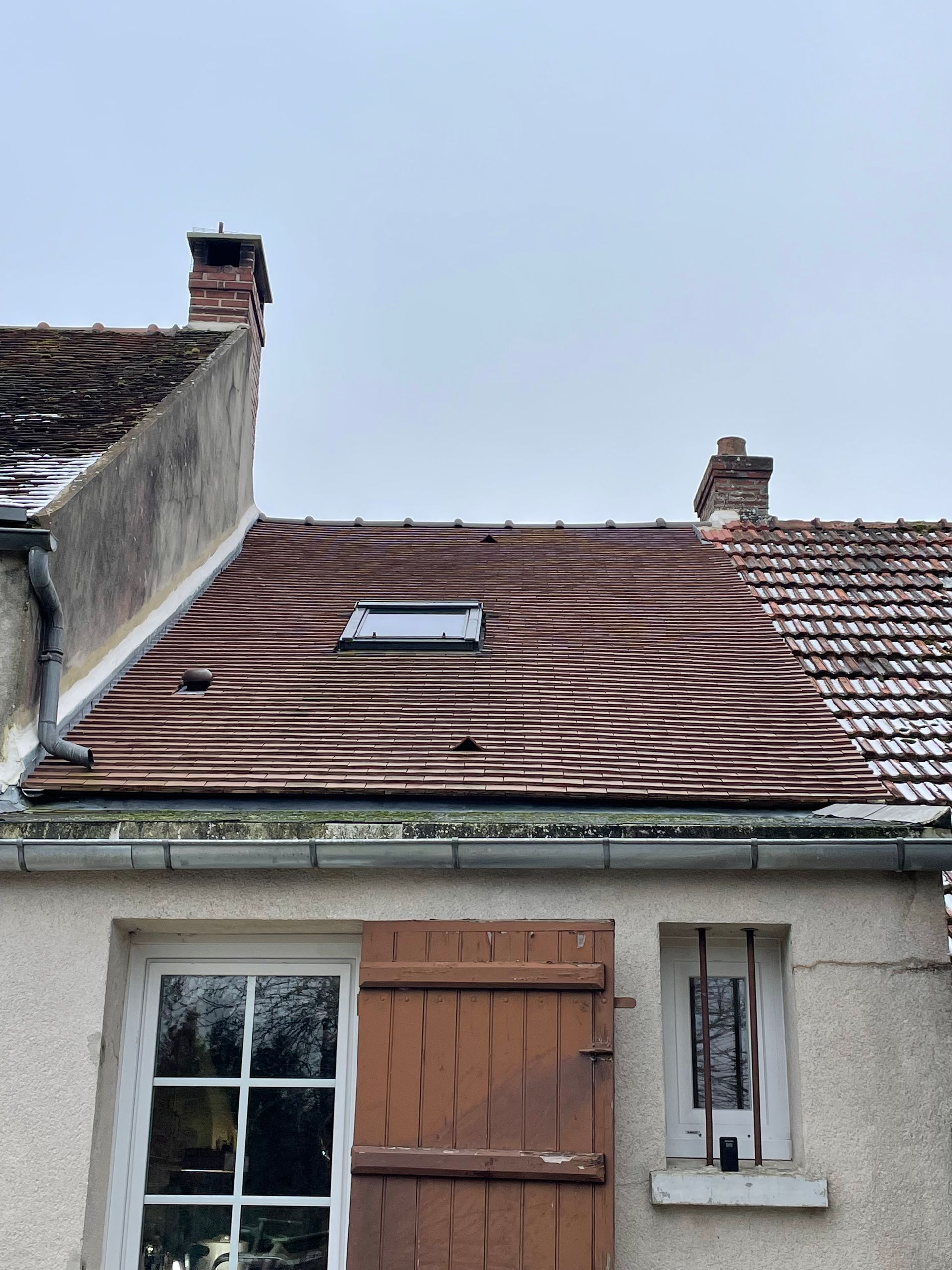 Deux ouvriers réparent les tuiles rouges du toit d'une maison au coucher du soleil