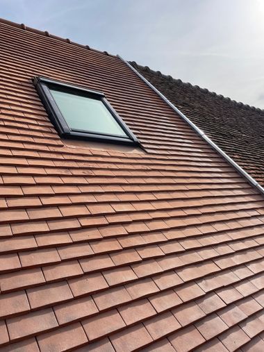 Toiture en tuiles rouges et fenêtre de toit sur un toit en pente