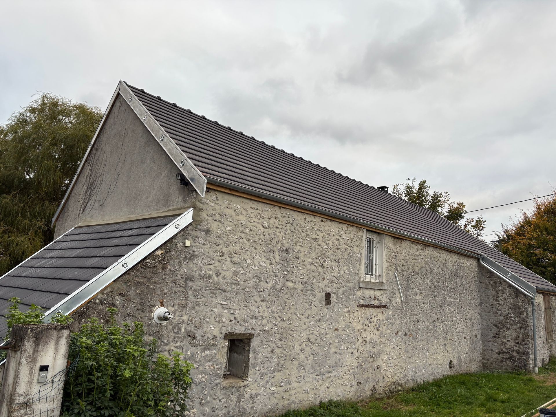 Bâtiment partiellement couvert de tuiles rouges empilées et de poutres en bois apparentes au coucher du soleil