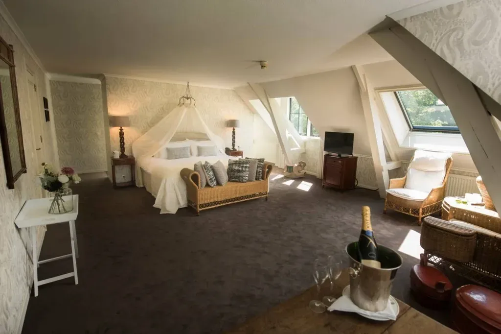 Hotelkamer met groot hemelbed, zithoek en champagne-emmer.