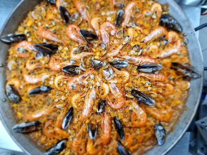 Paella con camarones, mejillones y arroz en una sartén grande.