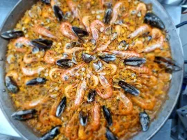 Paella con camarones, mejillones y arroz en una sartén grande.