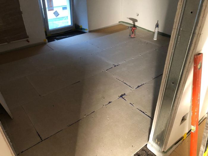 Una stanza in fase di ristrutturazione con un sacco di cartone sul pavimento.