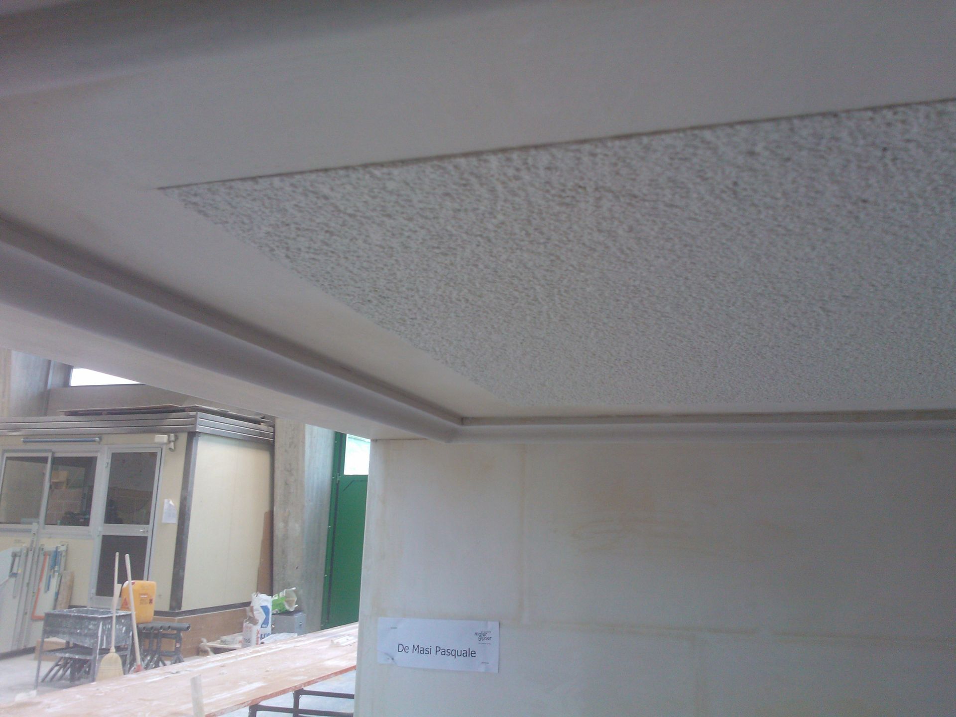 Due operai edili stanno installando il soffitto in una stanza.
