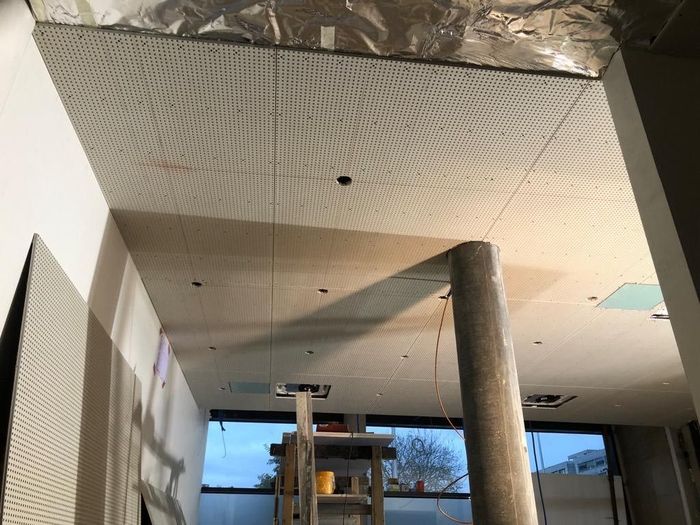 Un uomo sta dipingendo il soffitto di un soggiorno.
