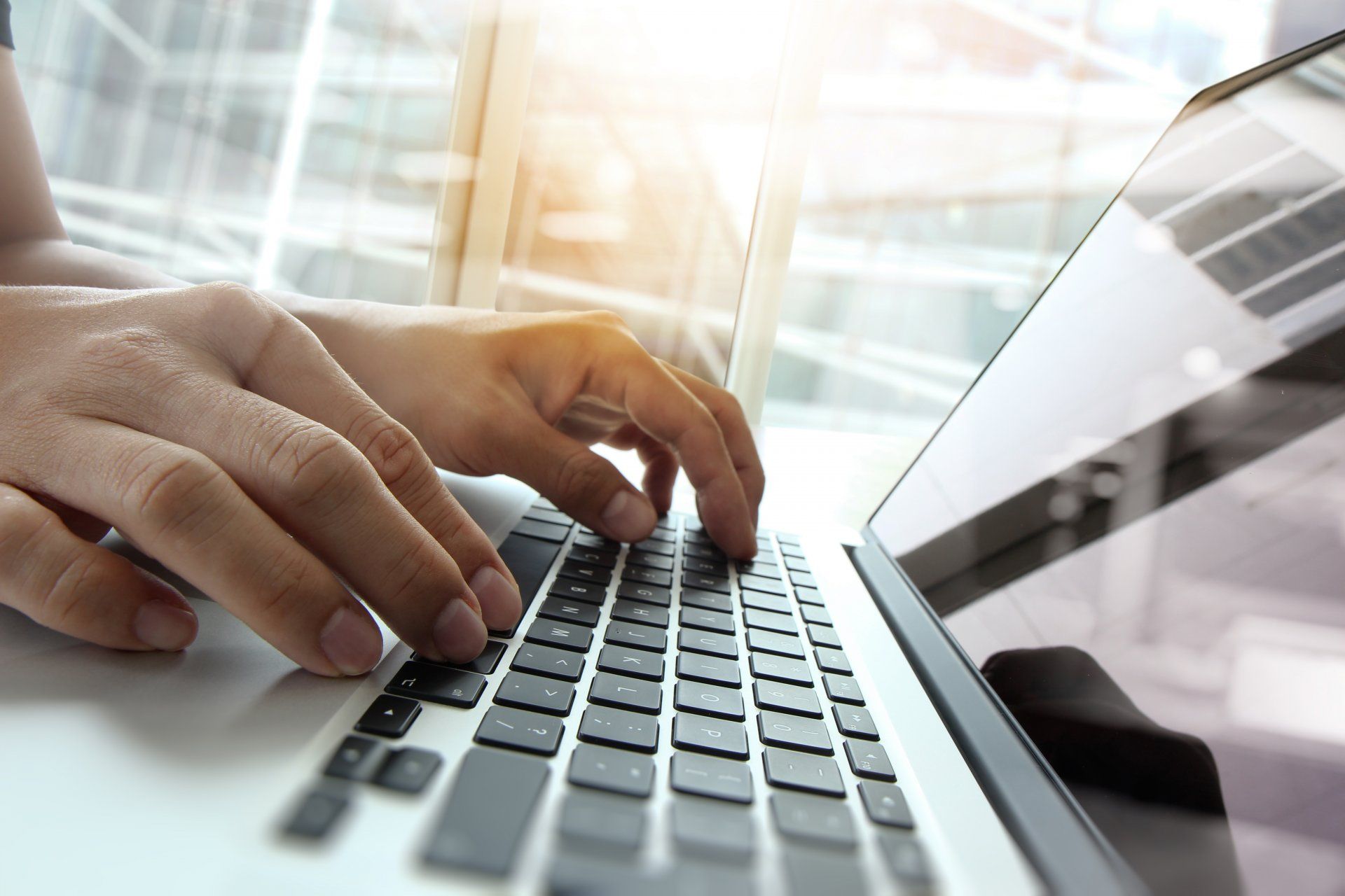 Une paire de mains tapant sur un clavier d'ordinateur portable.