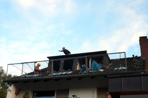 Zwei Männer arbeiten auf dem Dach eines Hauses.