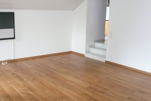 Ein leeres Wohnzimmer mit Holzböden und weißen Wänden