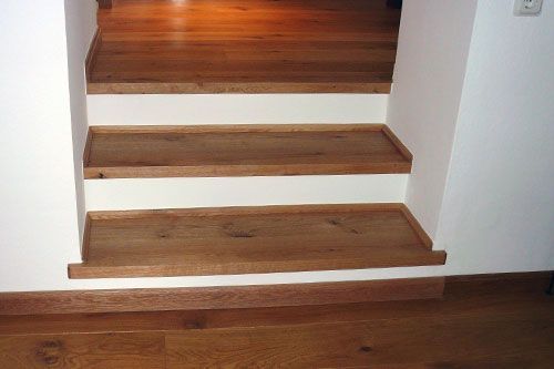 Eine Holztreppe führt zu einer weißen Wand hinauf.